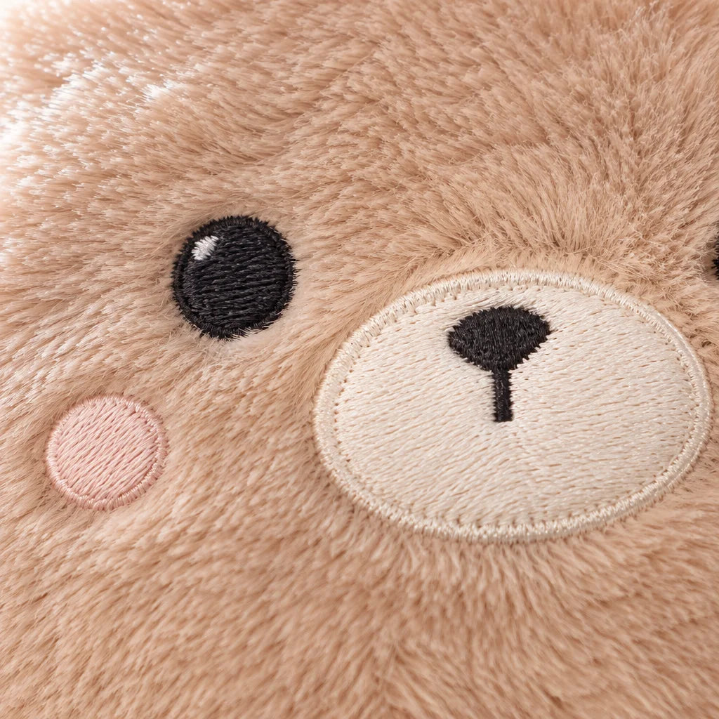 A macro photograph of the beige Ondine bear cover's embroidered face, tightly framed so the pale muz