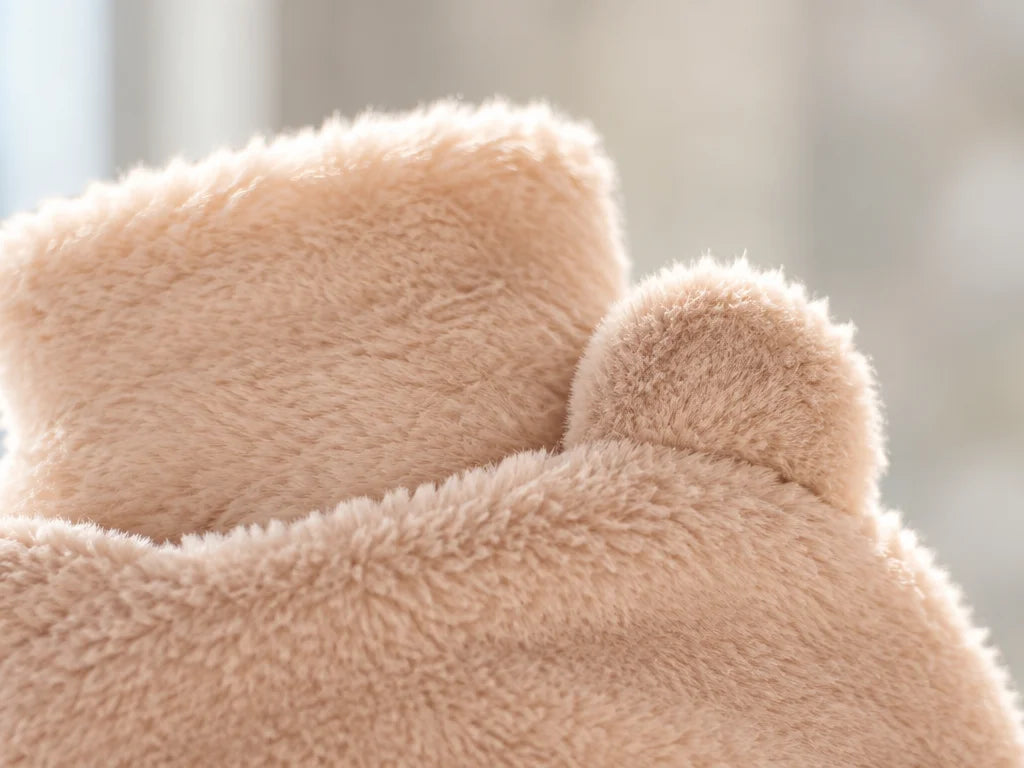 A close landscape macro photograph of the upper edge of the beige bear-shaped Ondine cover, showing