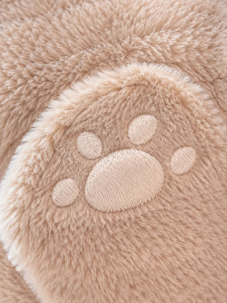 A macro photograph of the embroidered paw on the beige Ondine bear-shaped hot-water bottle. The roun